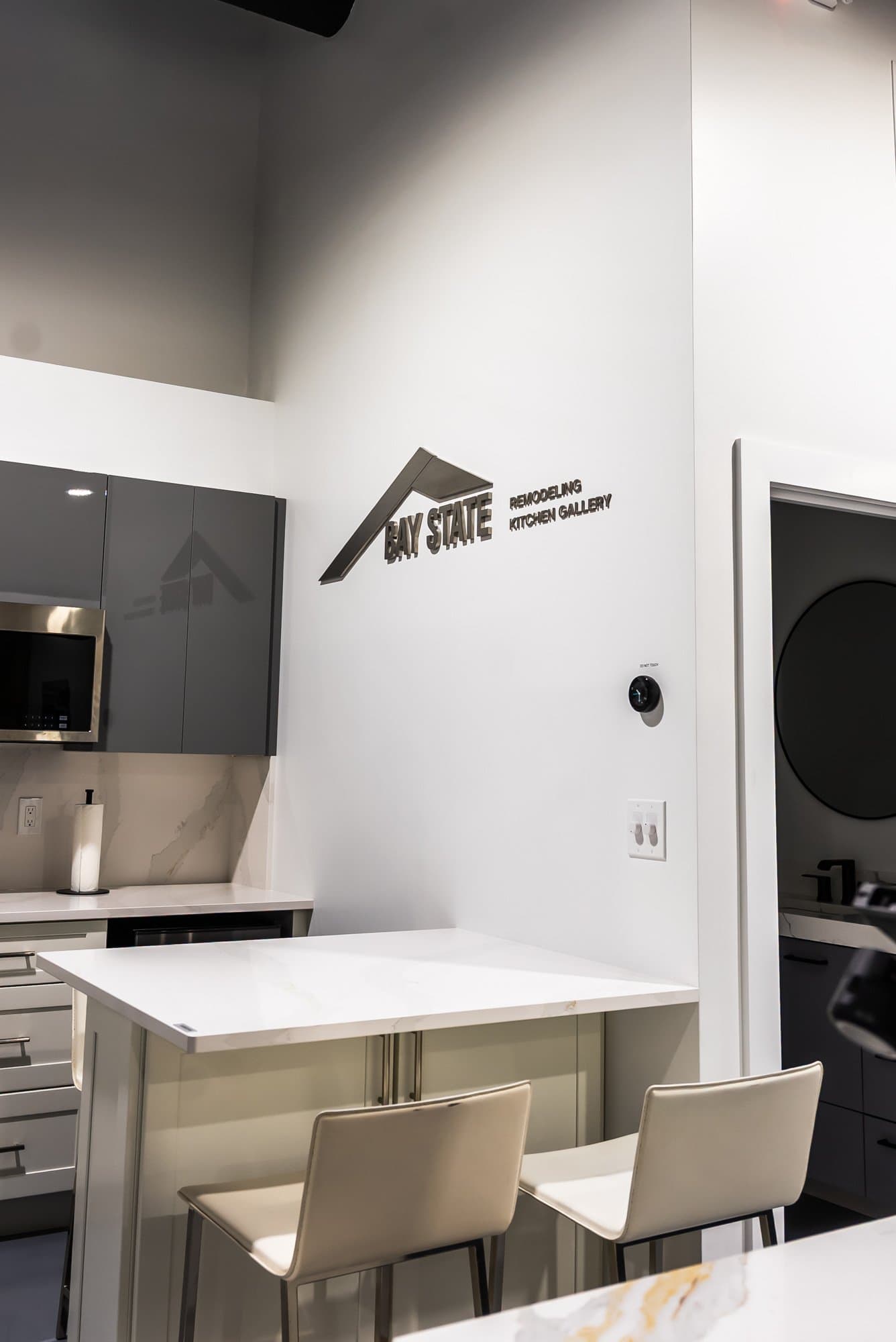 A white kitchen display with an island and stools in the Bay State Kitchen Gallery showroom in Waltham