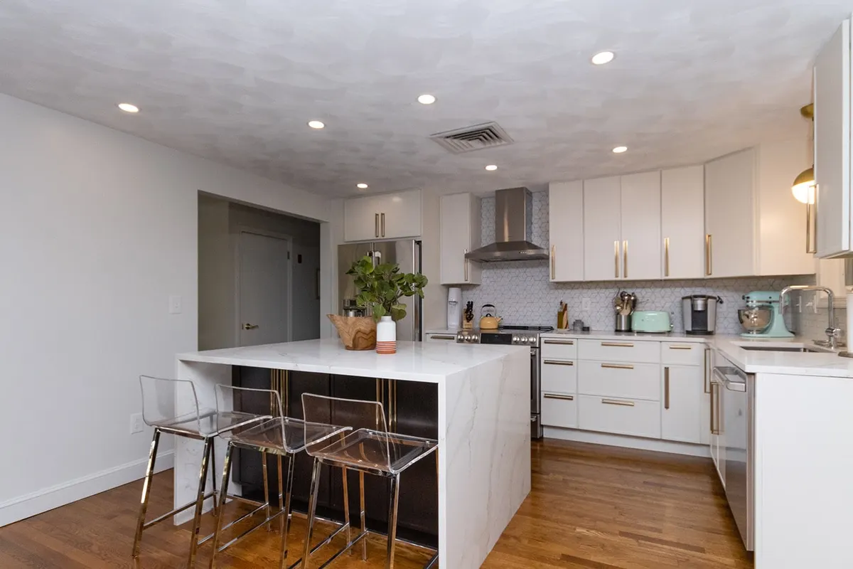 Modern white kitchen with a dark waterfall island, Chestnut Hill