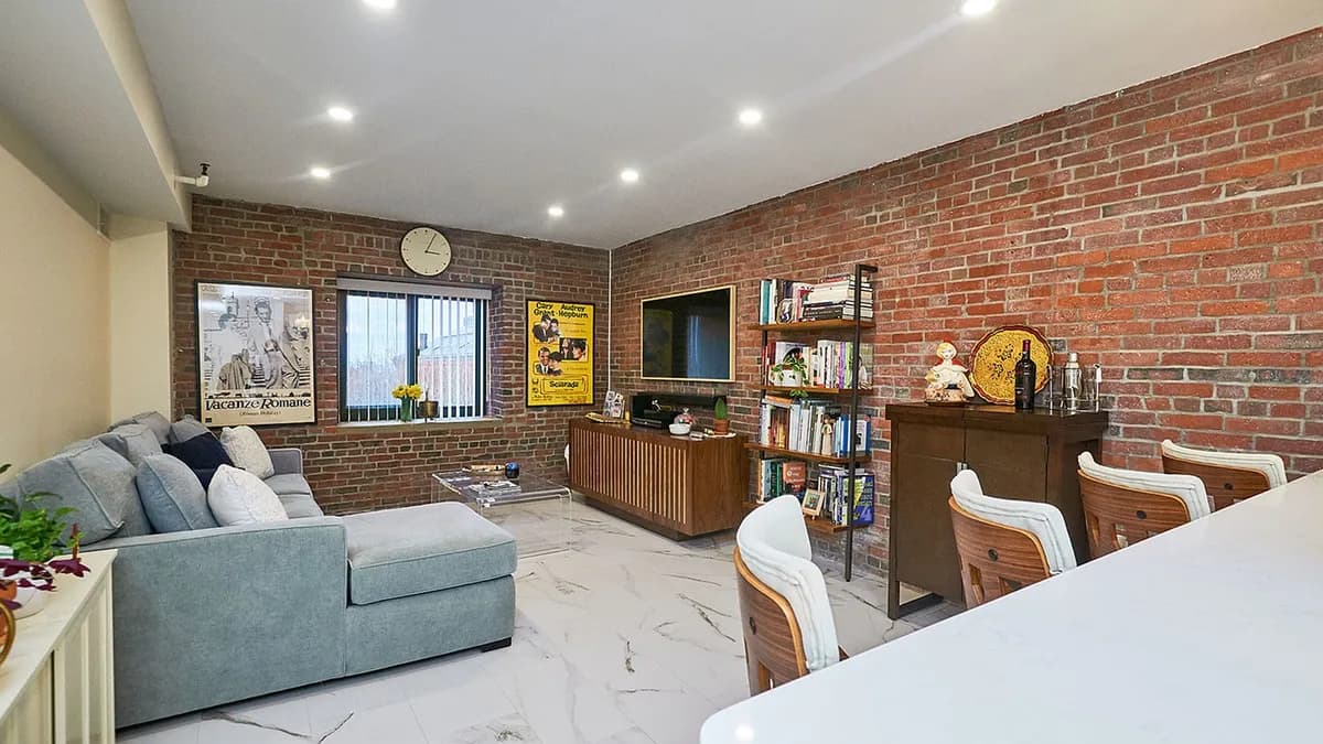 Charlestown lounge area with an exposed brick wall, gray sectional sofa, and wood credenza