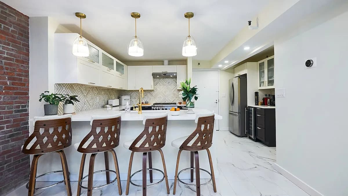 Charlestown kitchen with cream cabinets, a diamond-pattern marble backsplash, brass pendants, and exposed brick wall