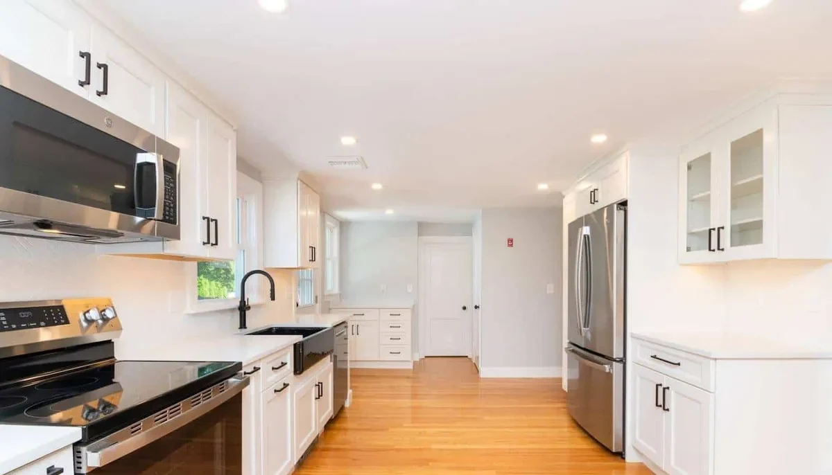Waltham kitchen with white shaker cabinets, black countertops, and stainless steel appliances throughout