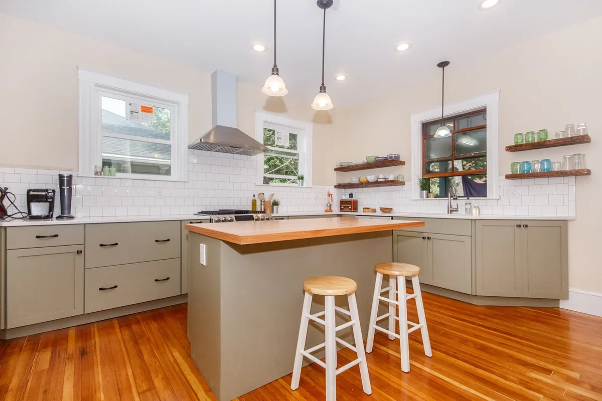 Jamaica Plain kitchen with sage green shaker cabinets, white subway tile, and a butcher block island