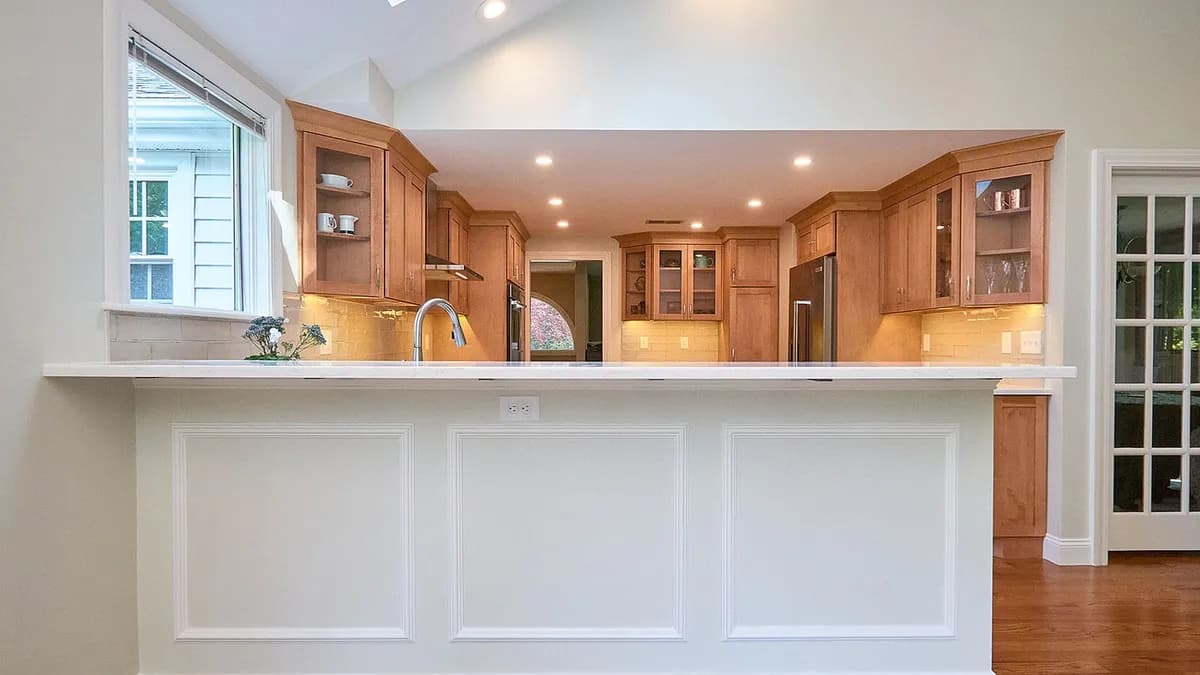 Wellesley kitchen pass-through with oak cabinets, white raised-panel counter, and subway tile backsplash