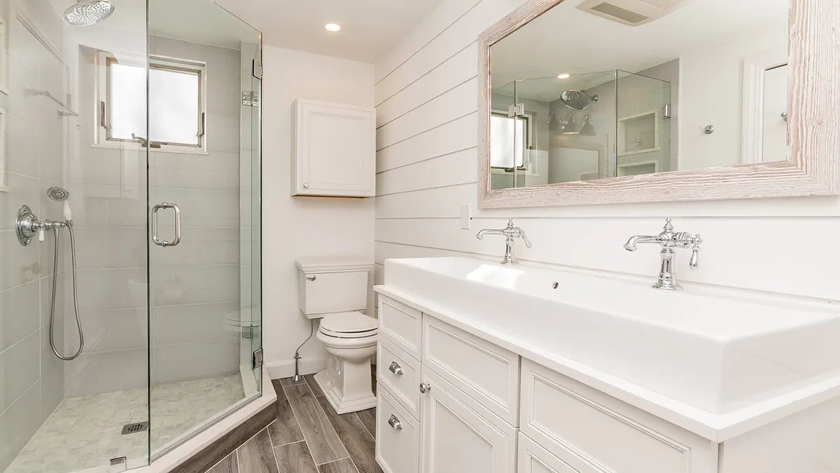 Belmont bathroom with a glass shower, wood-framed mirror, and dual-faucet vanity