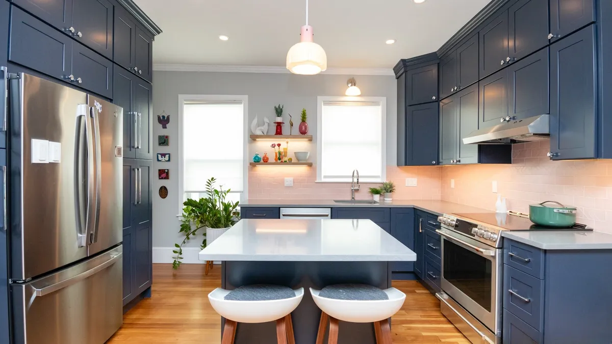Navy blue Jamaica Plain kitchen with white quartz counters, pink tile backsplash, and open wood shelving