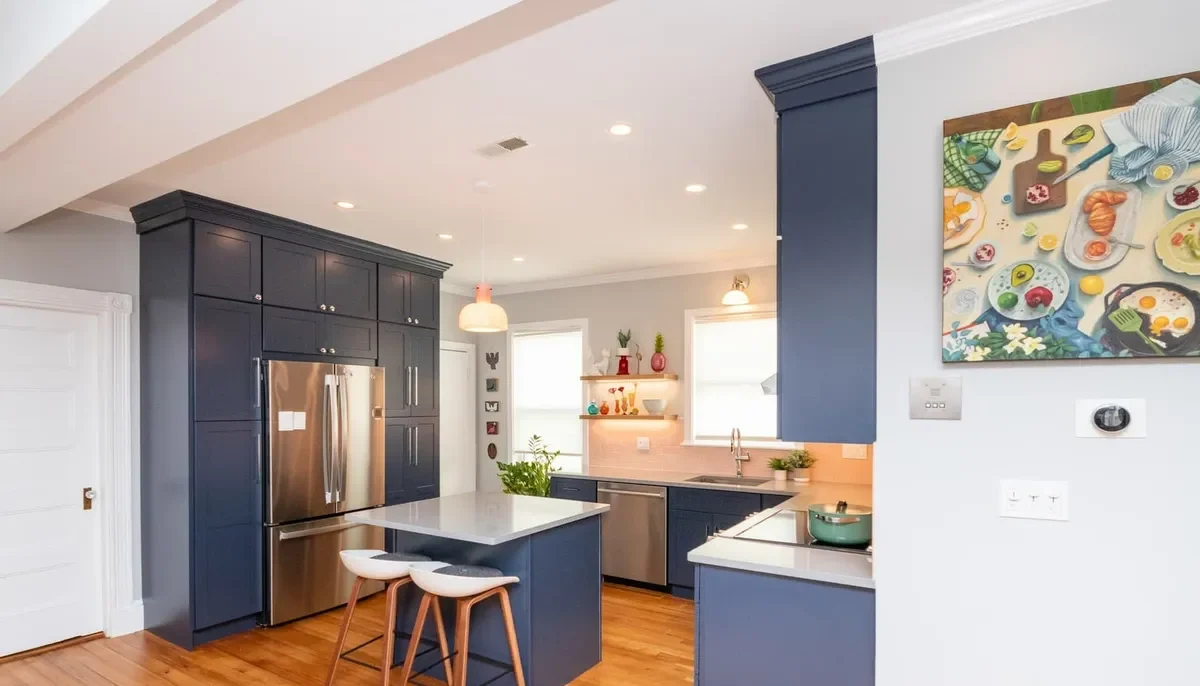 Wide view of the navy Jamaica Plain kitchen with island seating, stainless fridge wall, and pink tile backsplash