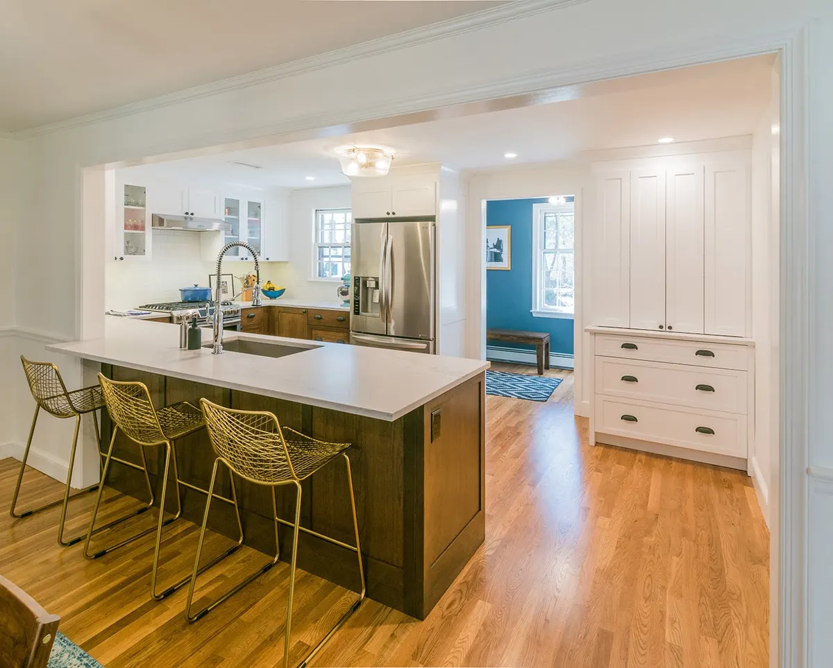 Walnut island with gold wire stools, open to a blue dining room — Wayland