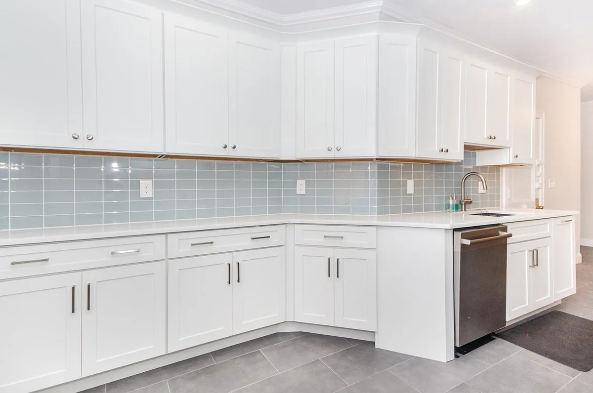 Brookline kitchen with white shaker cabinets, light blue subway tile backsplash, and quartz counters