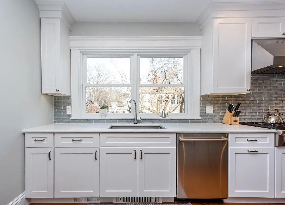 Newton kitchen with white shaker cabinets, gray linear tile backsplash, and quartz countertops