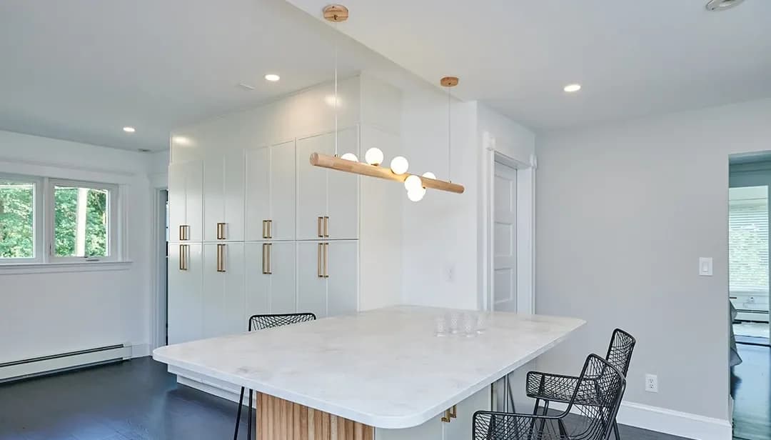 Newton kitchen island with a fluted wood base, marble-look quartz top, and brass-pulled white cabinetry