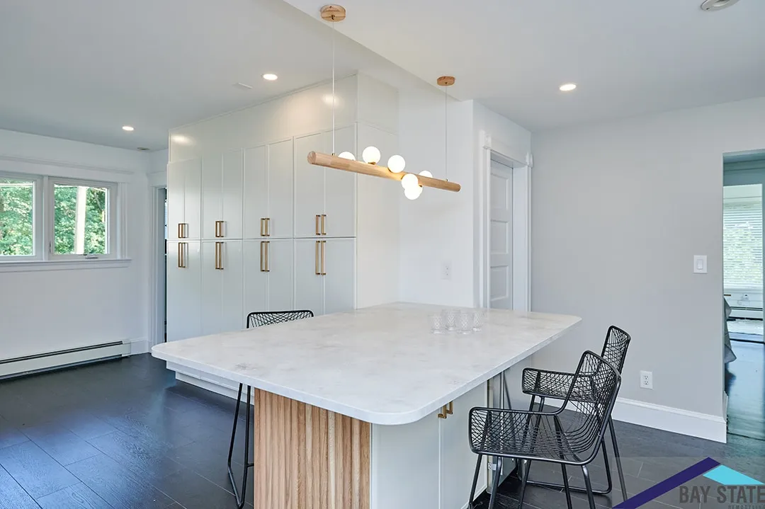 Newton kitchen island with a fluted wood base, marble-look quartz top, and brass-pulled white cabinetry
