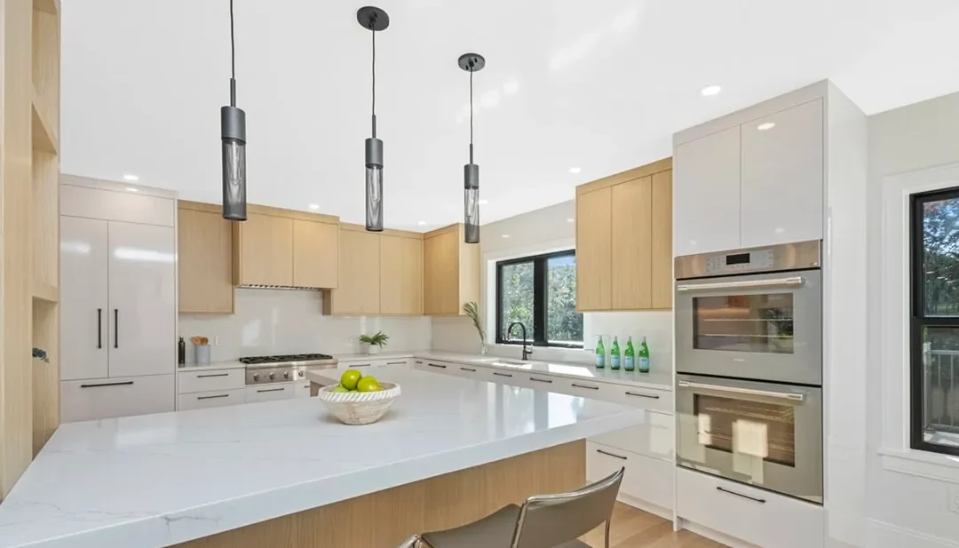 Newton kitchen with light oak cabinets, a white quartz waterfall island, and black cylinder pendants