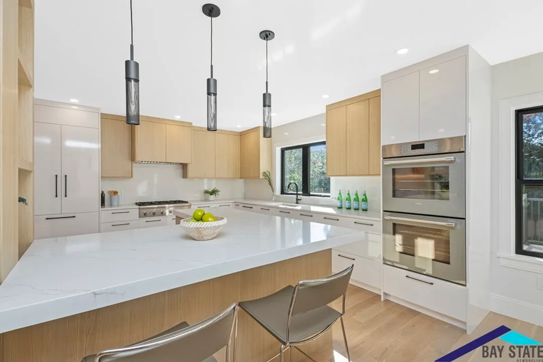 Newton kitchen with light oak cabinets, a white quartz waterfall island, and black cylinder pendants