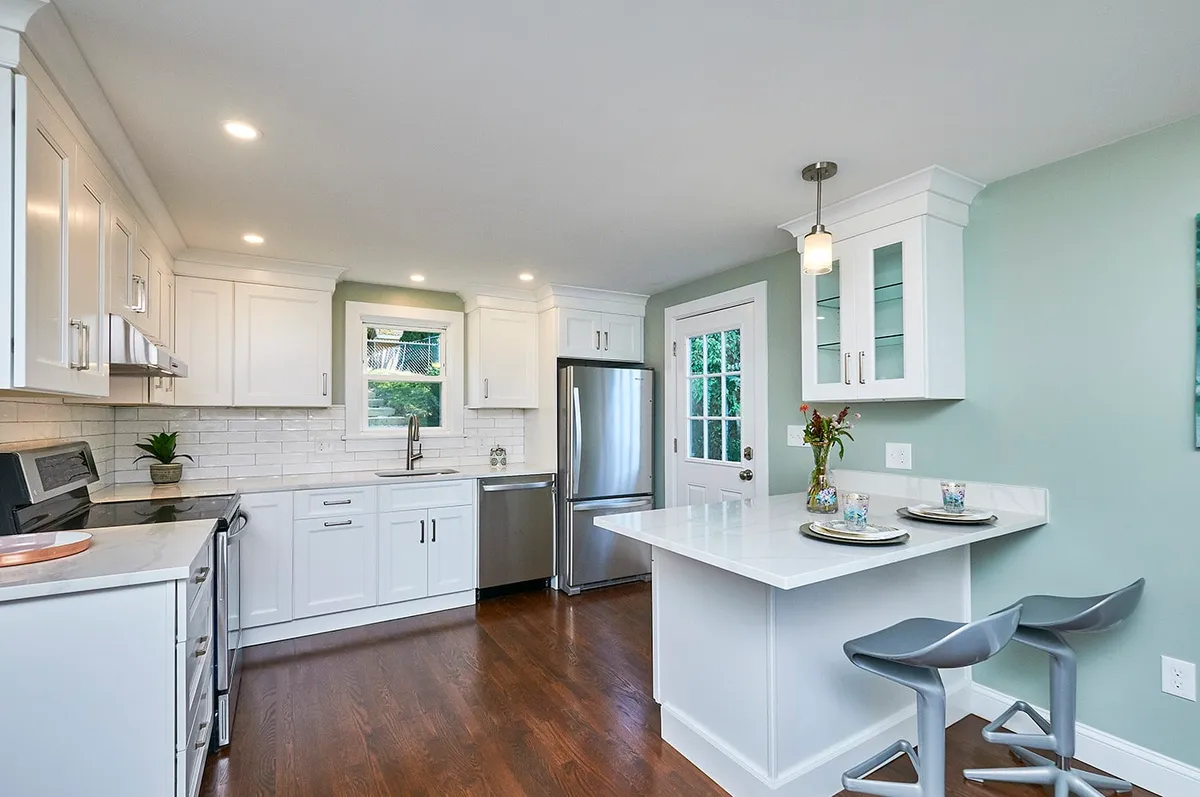 Waltham kitchen with white cabinets, subway tile backsplash, a stainless fridge, and sage green accent wall