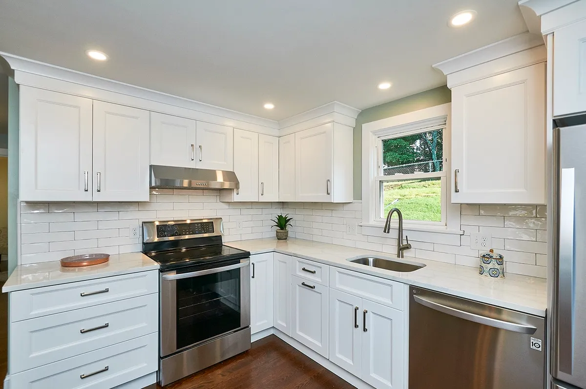 Waltham kitchen with white shaker cabinets, subway tile backsplash, quartz counters, and a black electric range