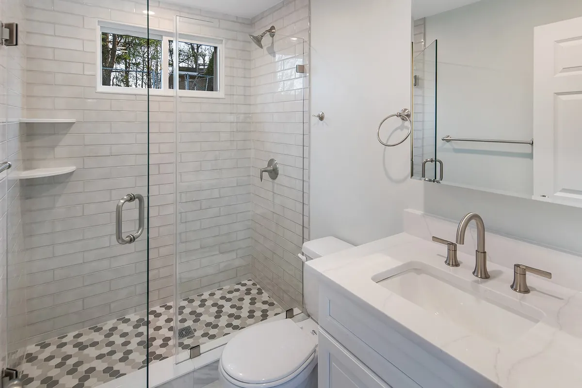 Waltham bathroom with a white subway-tile glass shower, marble-top vanity, and hexagon mosaic tile floor