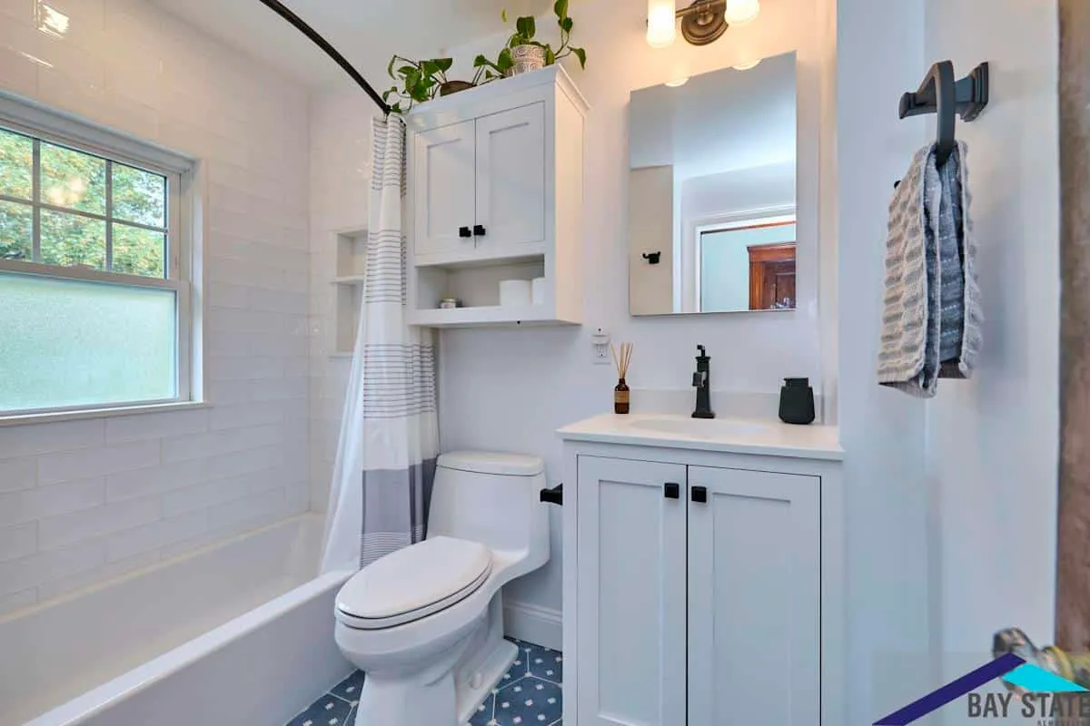 Renovated Brighton bathroom with a tub and shower, white vanity, and blue mosaic tile flooring