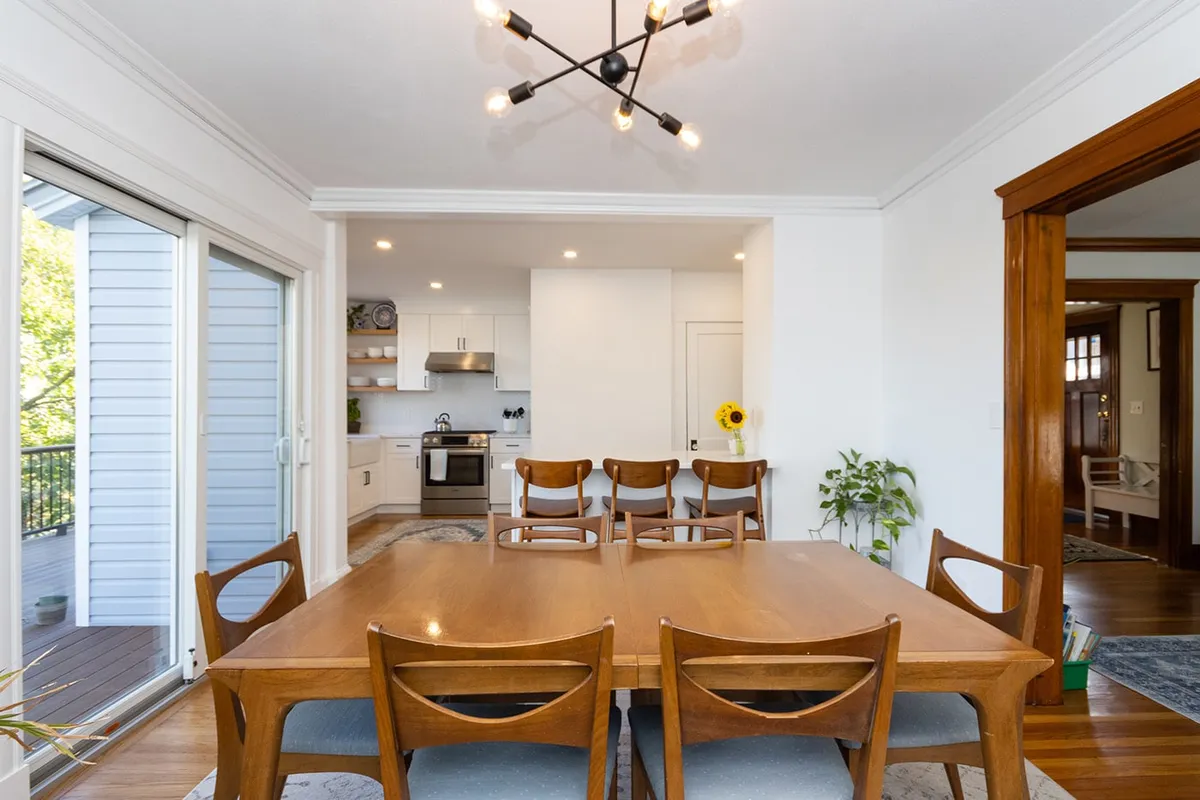 Brighton dining room with a wood table and chairs, plus a glimpse of white kitchen cabinets