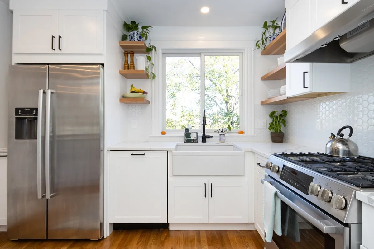 Brighton kitchen with white cabinets, a farmhouse sink, hexagon tile backsplash, and open wood shelving