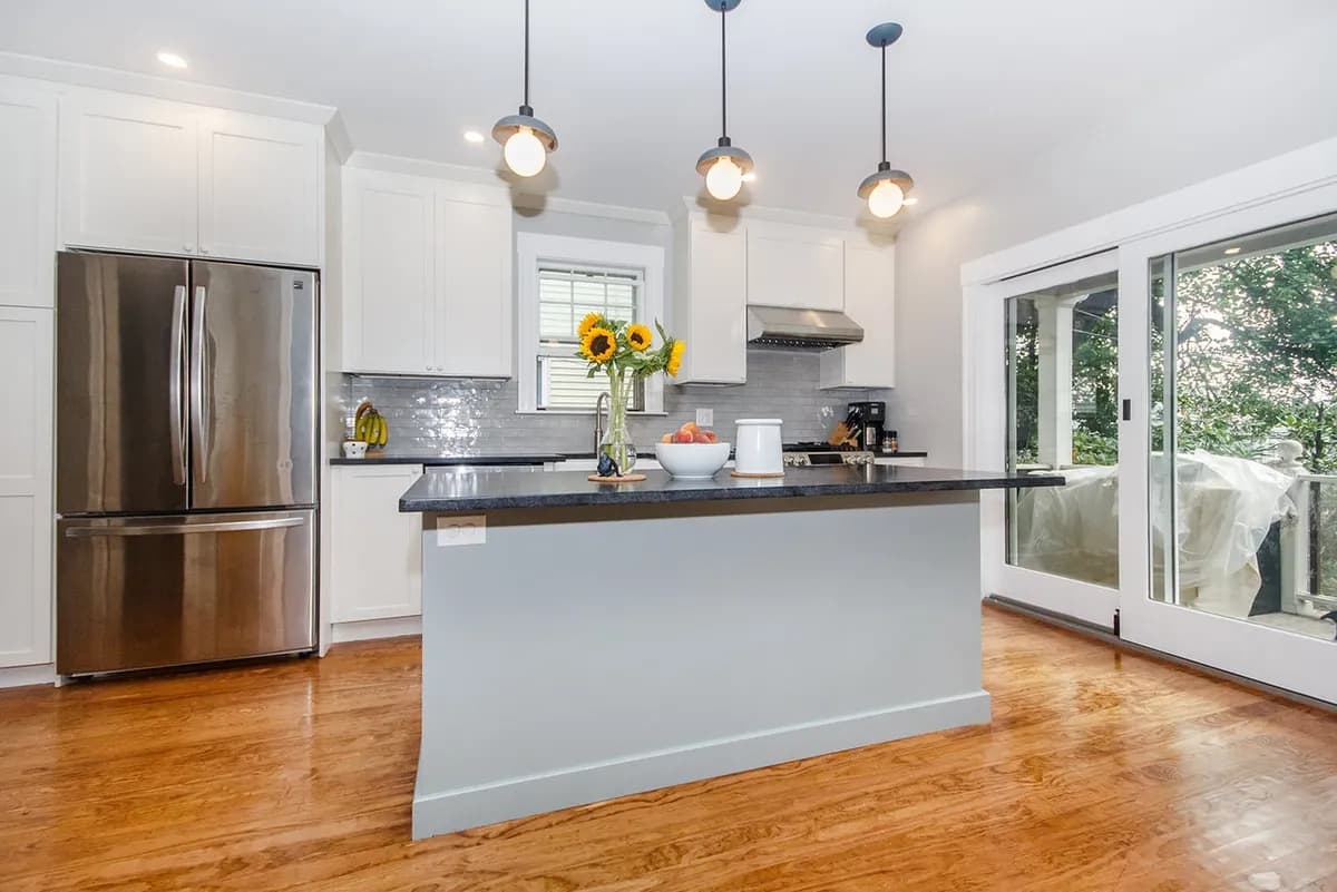 Close view of a Roslindale kitchen island with dark stone counter and globe pendant lighting