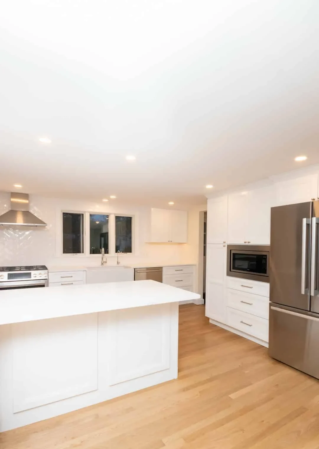 Newton kitchen with glossy white cabinets, a quartz waterfall island, and a stainless French-door refrigerator