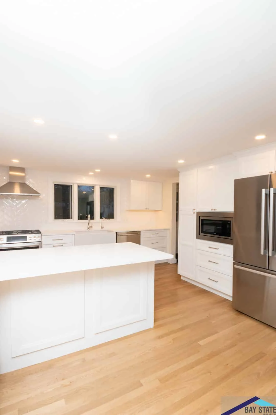 Newton kitchen with glossy white cabinets, a quartz waterfall island, and a stainless French-door refrigerator