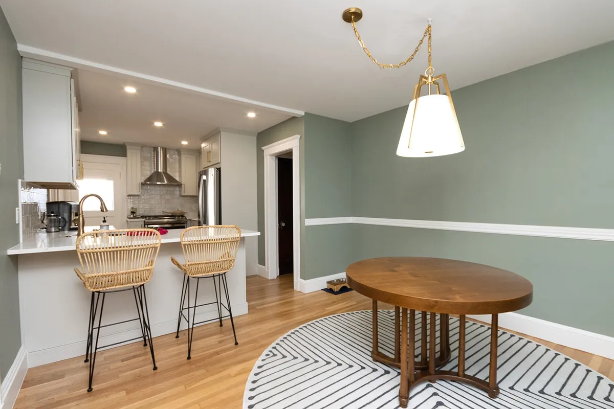 West Roxbury eat-in kitchen with sage green walls, a round wood table, and rattan chairs