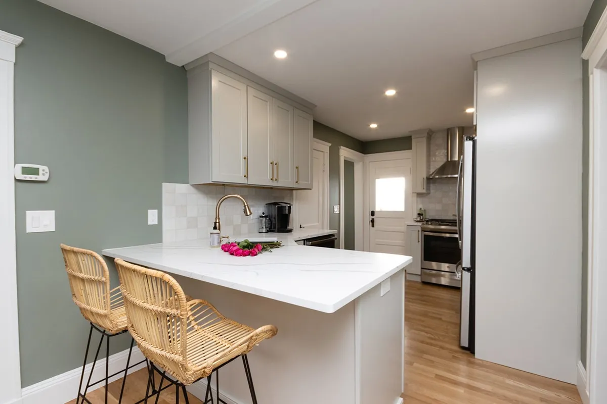 West Roxbury kitchen with white cabinets, brass hardware, quartz counters, tile backsplash, and a gas cooktop