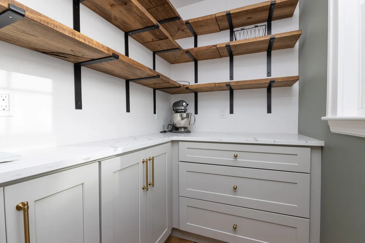 West Roxbury butler's pantry with gray shaker cabinets, brass hardware, quartz counters, and reclaimed wood shelving