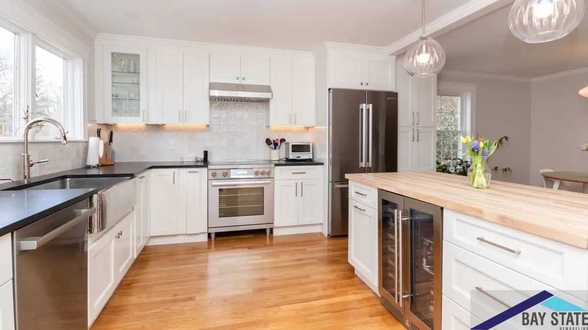 Renovated Newton kitchen with a butcher-block island, built-in wine fridge, glass globe pendants, and stainless appliances