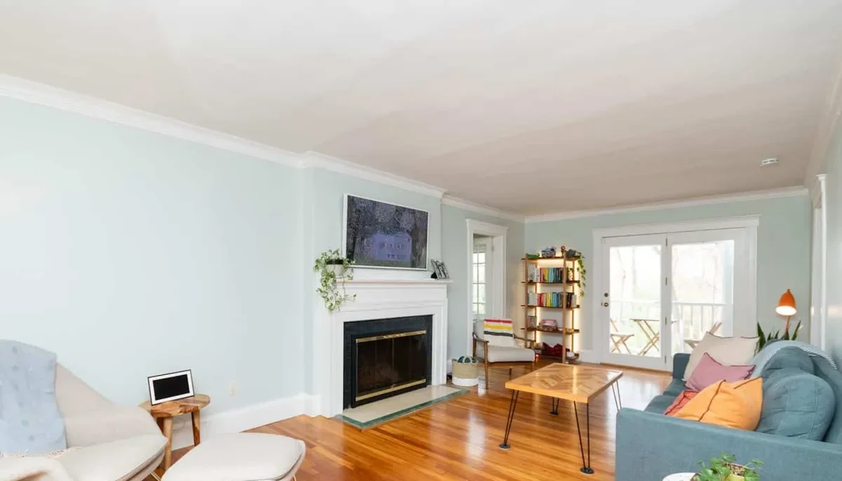 Adjoining Newton living room with a wood-mantel fireplace, hardwood floors, and French doors to the deck