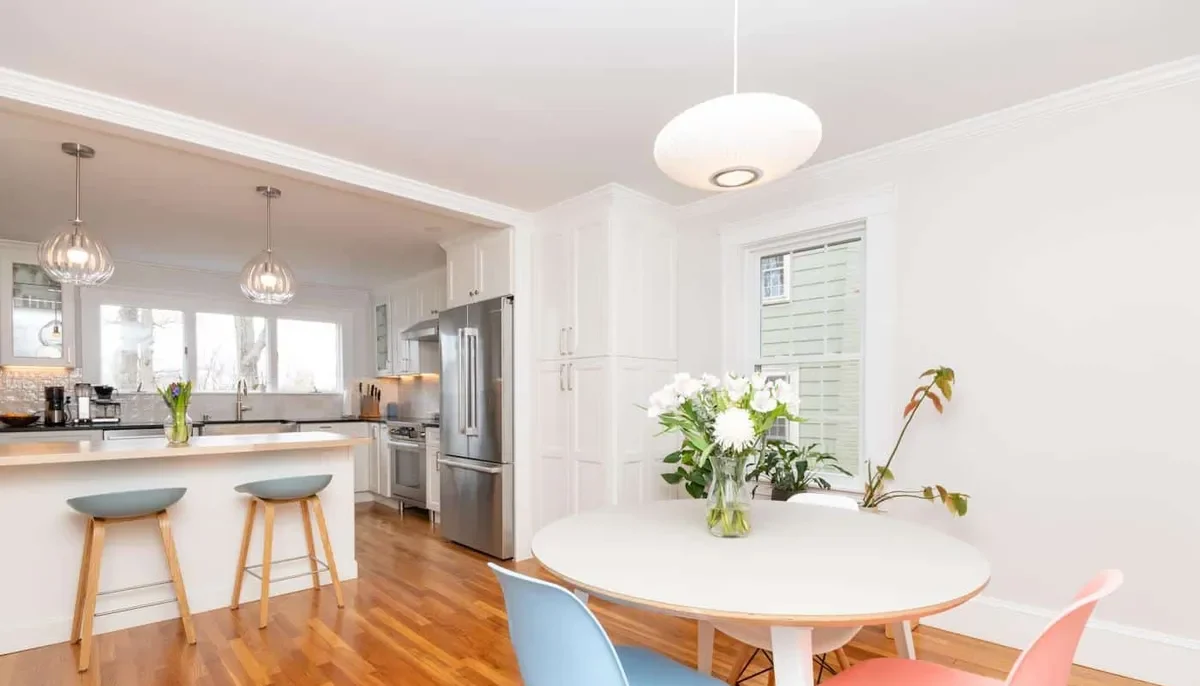 Open dining nook off the Newton kitchen with a round table, colorful chairs, and a globe pendant light