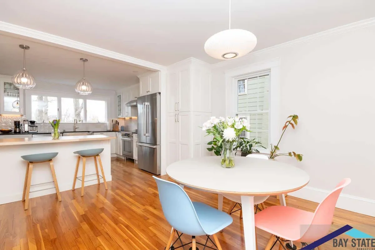 Open dining nook off the Newton kitchen with a round table, colorful chairs, and a globe pendant light