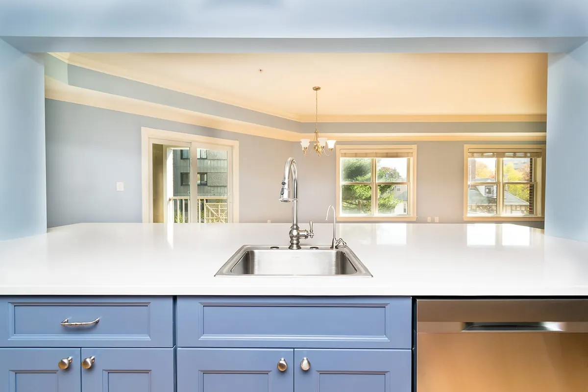 Brookline kitchen sink with a gooseneck faucet, blue cabinets, and a view into open dining space