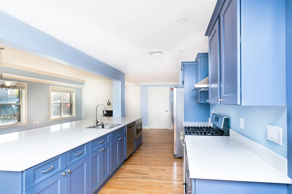 Brookline galley kitchen with periwinkle blue cabinets, white quartz counters, and a stainless gas range