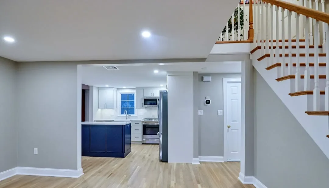 View of the navy island Arlington kitchen from the foyer, with white cabinets and hardwood floors throughout