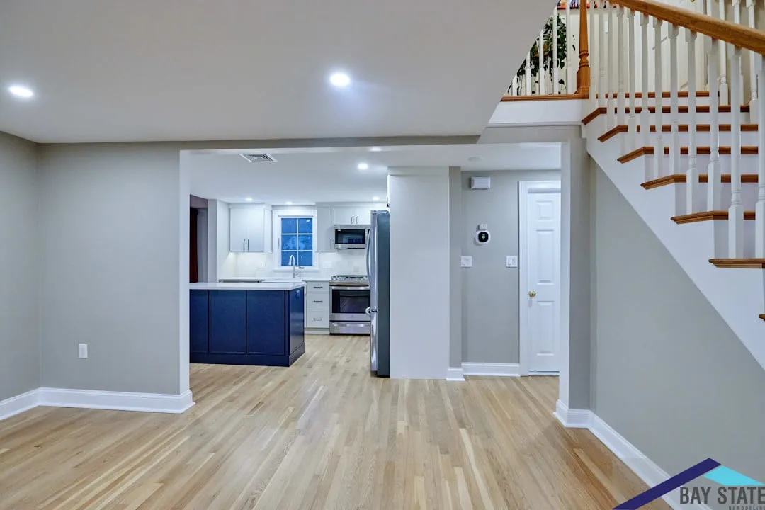 View of the navy island Arlington kitchen from the foyer, with white cabinets and hardwood floors throughout