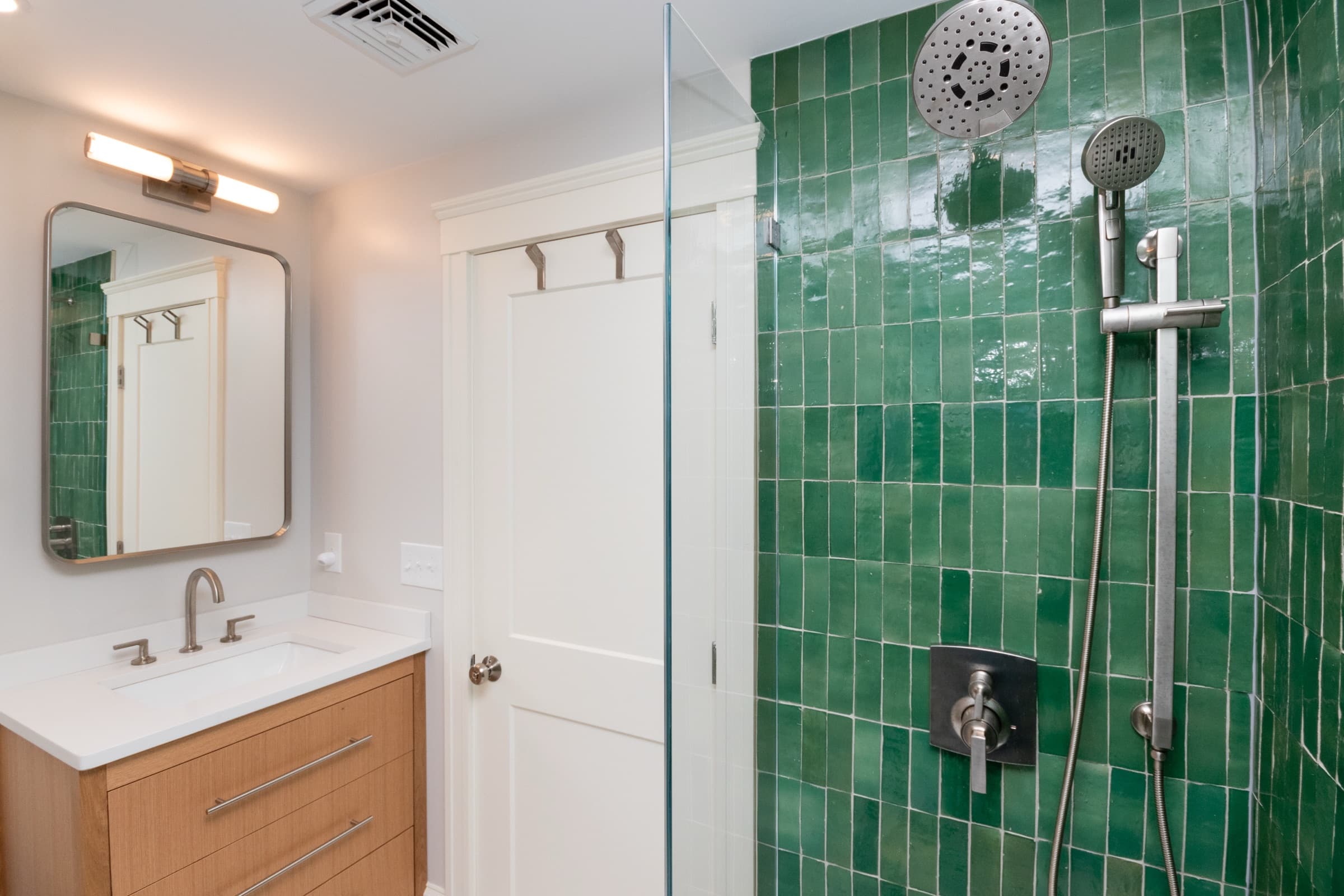 Finished bathroom with a green zellige-tiled shower and a wood vanity on Trowbridge Ave., Newton