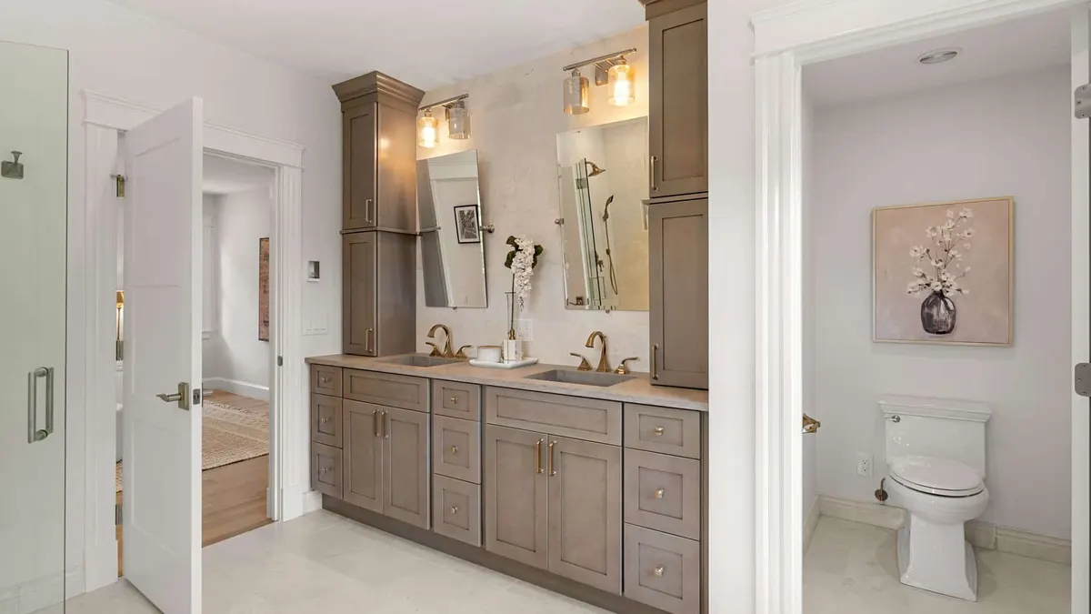 Bathroom double vanity with dark wood cabinets, twin mirrors, and quartz countertop