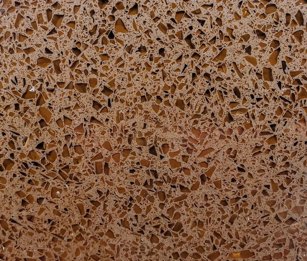 Close-up of quartz countertop with warm amber terrazzo-style stone chips and white veining